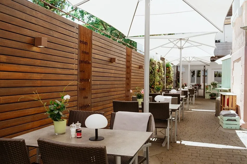 Terrasse des Kartoffelhauses Freiburg mit Tischen und Sonnenschirmen